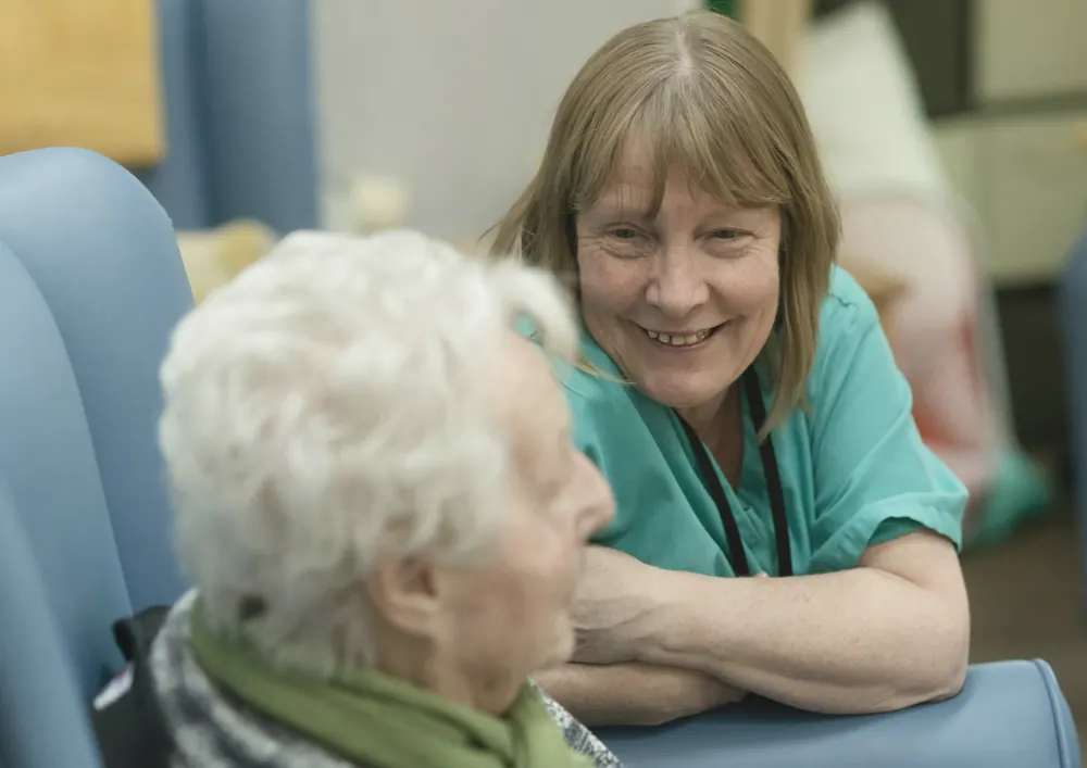 A caregiver smiles while talking with an older resident